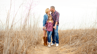 Gary Heyer and wife kissing while holding their daughter