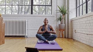 Fit senior woman taking online yoga