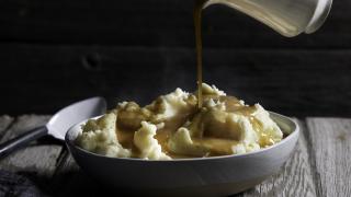 Gravy being poured over the dish of mashed potatoes