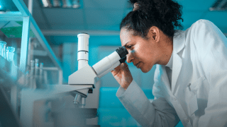 A City of Hope researcher looks through a microscope