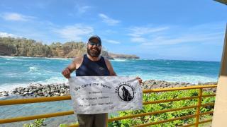 City of Hope colon cancer patient Jason Randall holds a Man Up to Cancer banner with the ocean behind him
