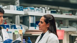 Two scientists in lab coats reviewing data, their expressions focused and engaged.
