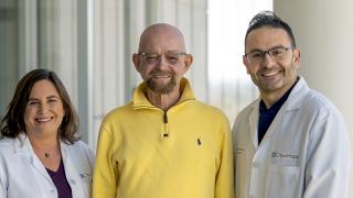 Patient, Paul Edmonds, standing beside Dr. Jana Dickter (left), and Dr. Monzr M. Al Malki (right)