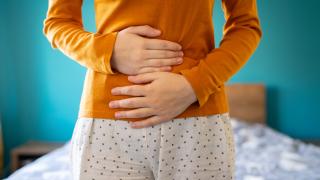 A young woman is having pain in her stomach and holding it with both hands