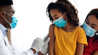image of a doctor vaccinating a child being held by a woman
