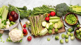 image of a variety of fresh green vegetables along with a few white and red vegetables scattered about