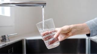 close up image of a person filling a glass of water from the tap