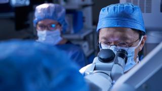 Doctors in operating room wear scrubs and face masks