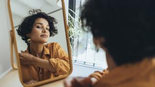image of a woman with curly hair looking at herself in a mirror