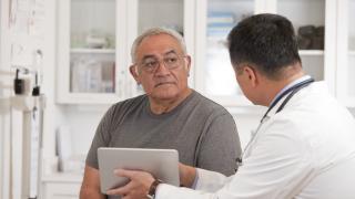 image of a doctor showing the screen of a small laptop to an older man