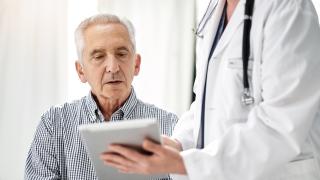 Doctor sharing electronic test results with patient using a tablet at a clinic.