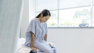 image of a woman in a hospital gown sitting on the edge of an examination table