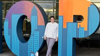 Young woman standing a smiling next to HOPE letters