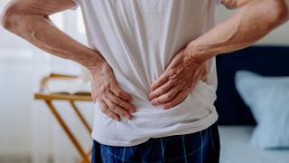 Man standing and clutching his lower back in pain