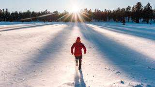 person in winter wear running through a field of snow