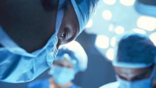 Masked surgeon performing surgery