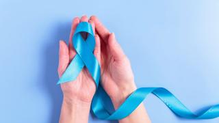 Female hands cupping a blue cancer ribbon