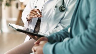 Physician reviewing information on a tablet with a patient