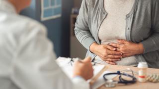 Female patient holding her stomach at a doctor's appointment