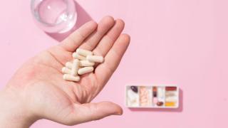 Person holding several pancreatic enzyme supplements in their hand