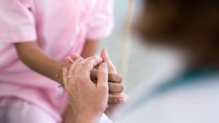Caretaker holding the hand of a cancer patient