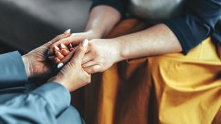 Two women holding both hands in a comforting way