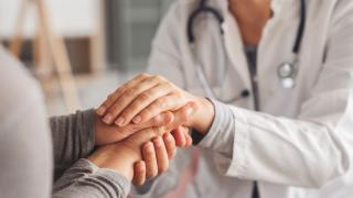 Physician comforting patient, holding their hand