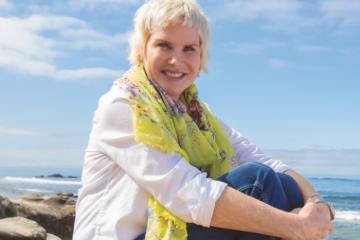 A woman sitting and smiling posed with her hands on knee