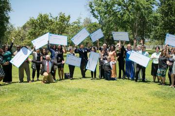Group photo of people holding large donoation checks