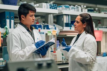 Two scientists in lab coats reviewing data, their expressions focused and engaged.